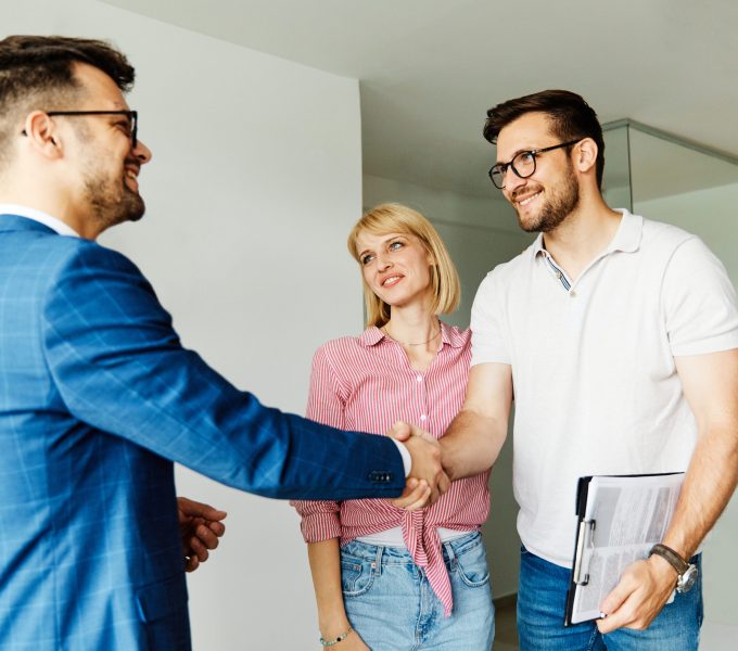 Young happy couple and an agent in a new property